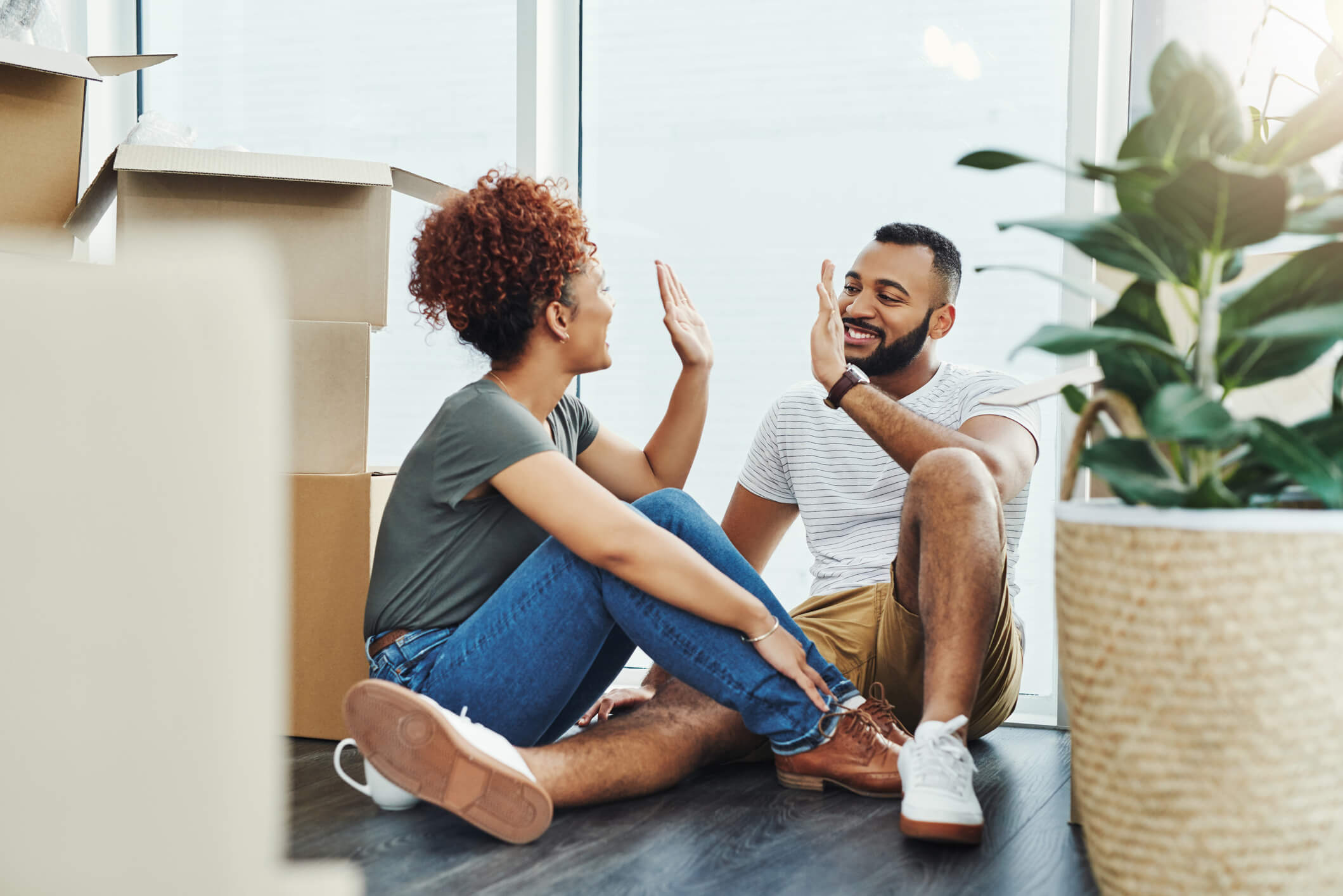 picture of a young couple sitting on the floor giving each other a high five