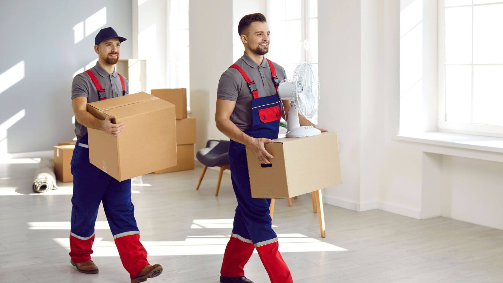 Professional movers carrying boxes in a home.