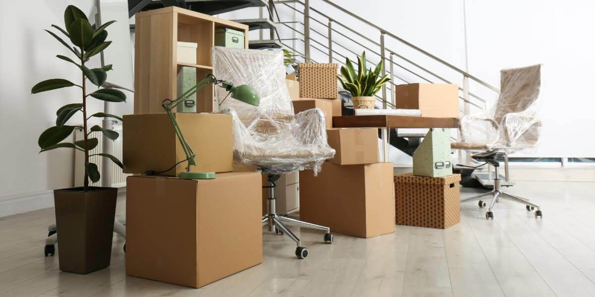 Office furniture and equipment packed in boxes and wrapped in plastic for relocation — illustrating what is commercial moving for businesses.