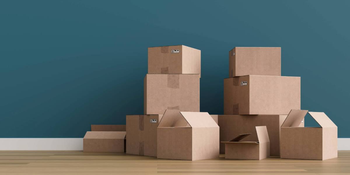 Stacked cardboard boxes against a teal wall, representing the planning and packing involved in residential moving vs commercial moving.