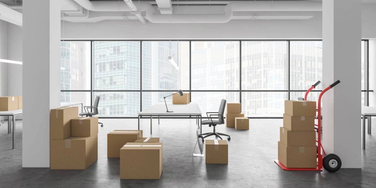 Stacked moving boxes and office furniture in a modern workspace representing commercial moving costs during an office relocation in 2025