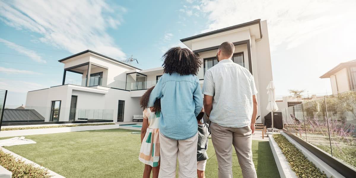 A family standing in front of a modern home after a white glove moving service carefully handled and delivered their belongings safely